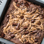 Tray of baked black bean brownies with a swirl of nut butter and chocolate chips.
