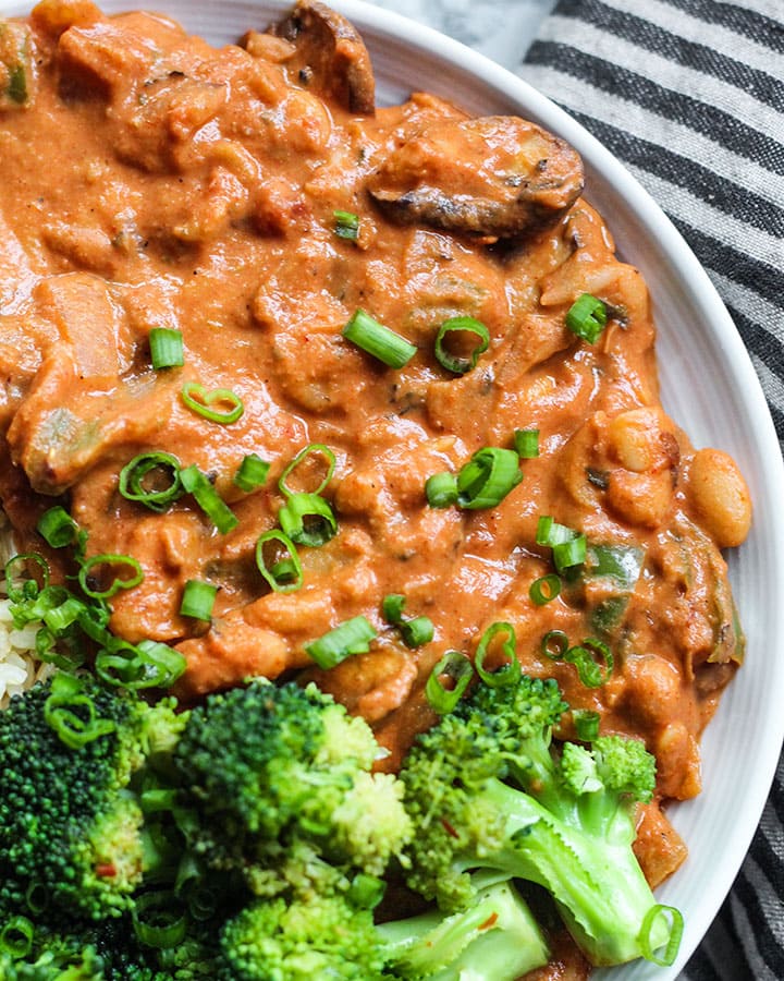 Up closse picture of cannellini tahini stew paired with broccoli and spring onions.