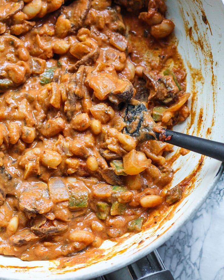 Cannellini tahini stew, mixed up in a cooking pan with a spatula.