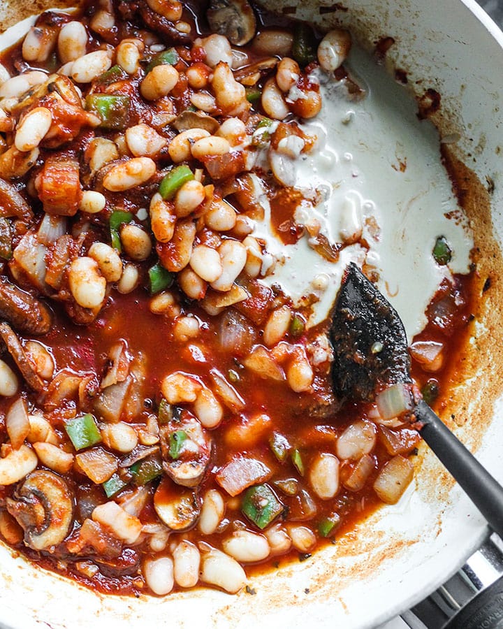 Tahini added to cannellini white bean stew, ready to be stirred in.