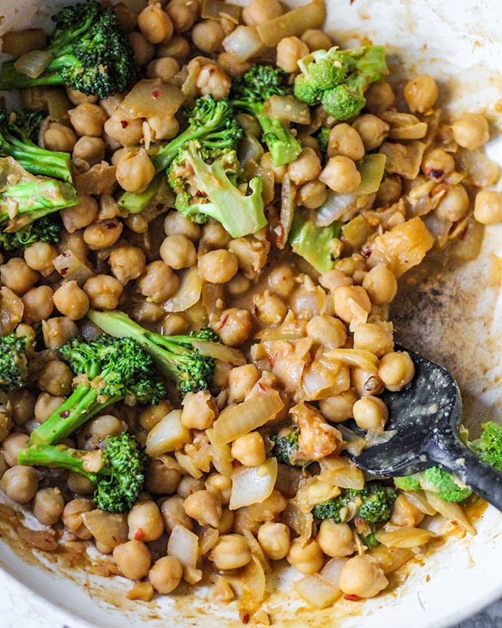 Peanut miso chickpeas with broccoli being sauteed in a pan.