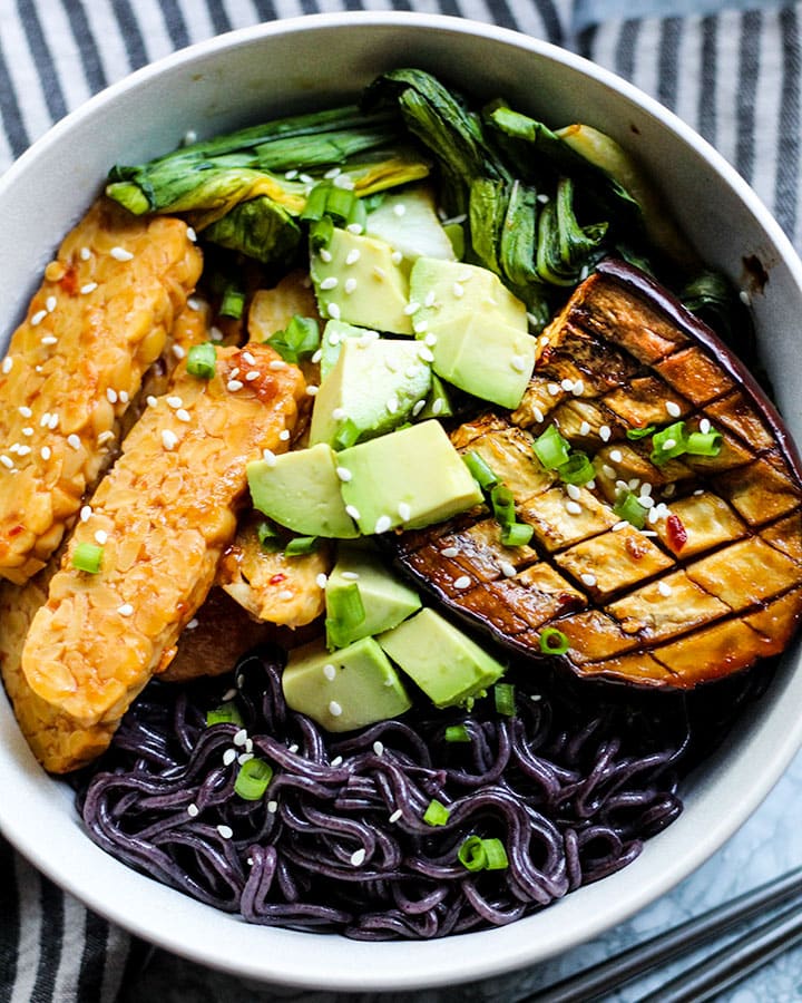 Bowl of miso eggplant, tempeh, boy choy, avocado and ramen shot at an angle.