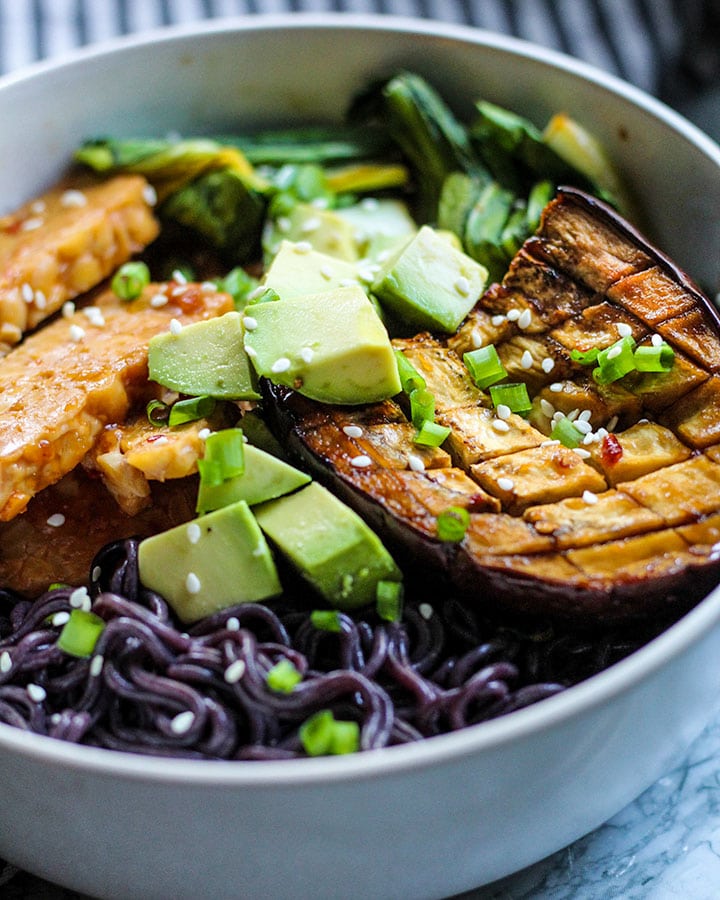 Bowl of ramen with tempeh, bok choy, avocado, and a slice of miso eggplant.