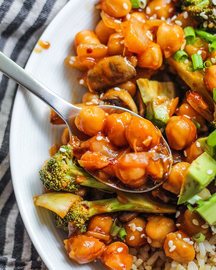 Sweet and sour chickpeas that are being scooped up from a plate.