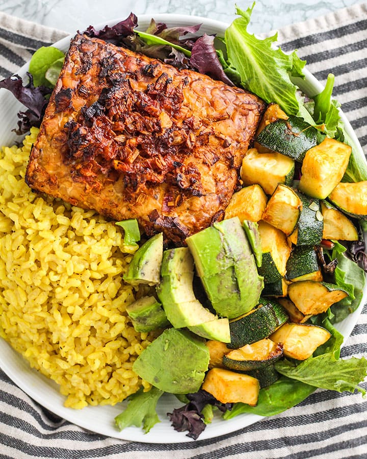 Baked tempeh paired with rice, avocado and sauteed zucchini.