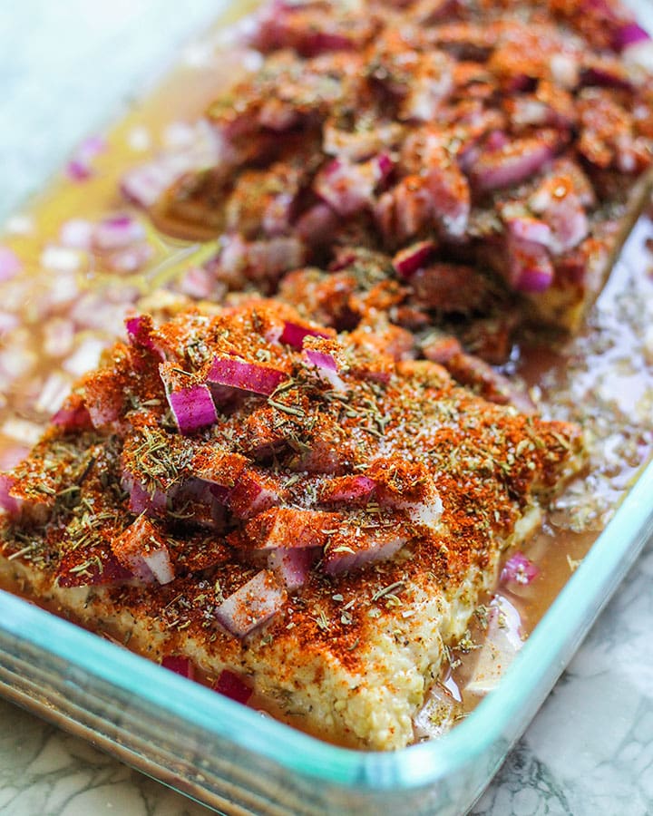 Tempeh topped with seasonings and onions.