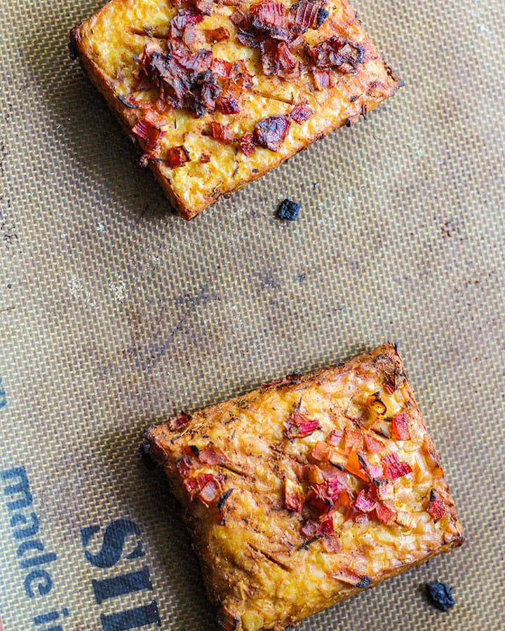 Two tempeh pieces fully baked and out of the oven sitting on a baking tray.