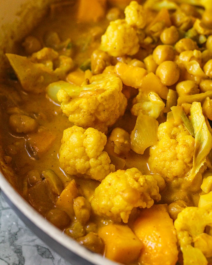 Close up of golden mango coconut chickpea curry in cooking pan.