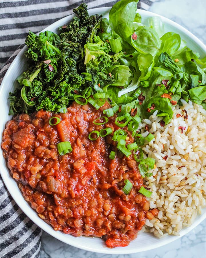 Chili plated with brown rice, sauteed kale, fresh greens and diced spring onions. 