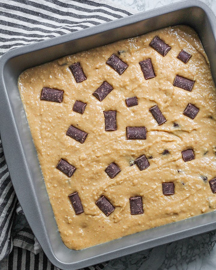 Blondie batter spread evenly in a baking tray and topped with extra dairy free chocolate chips.