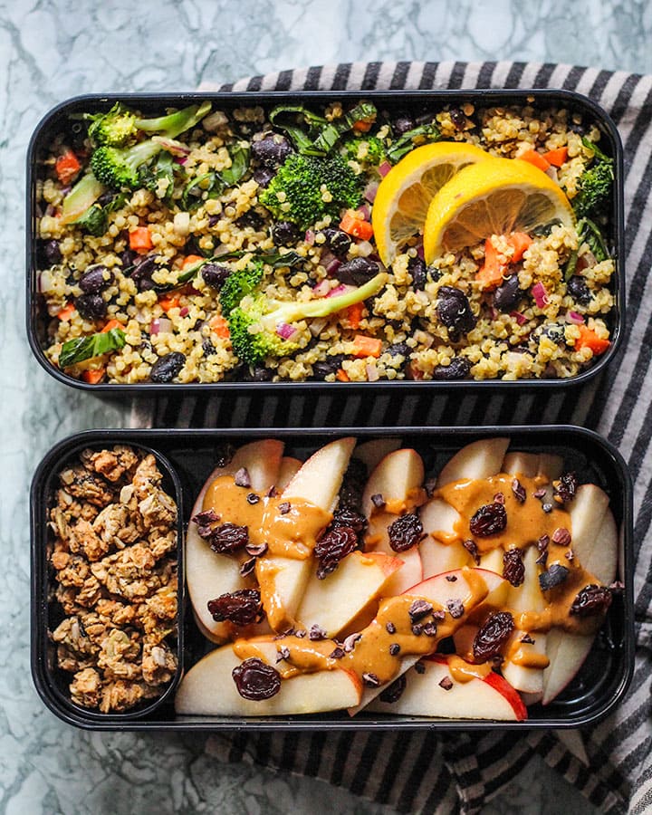 Quinoa salad placed in top half of bento box lunch container and paired with some apple nachos in the bottom lunch container.