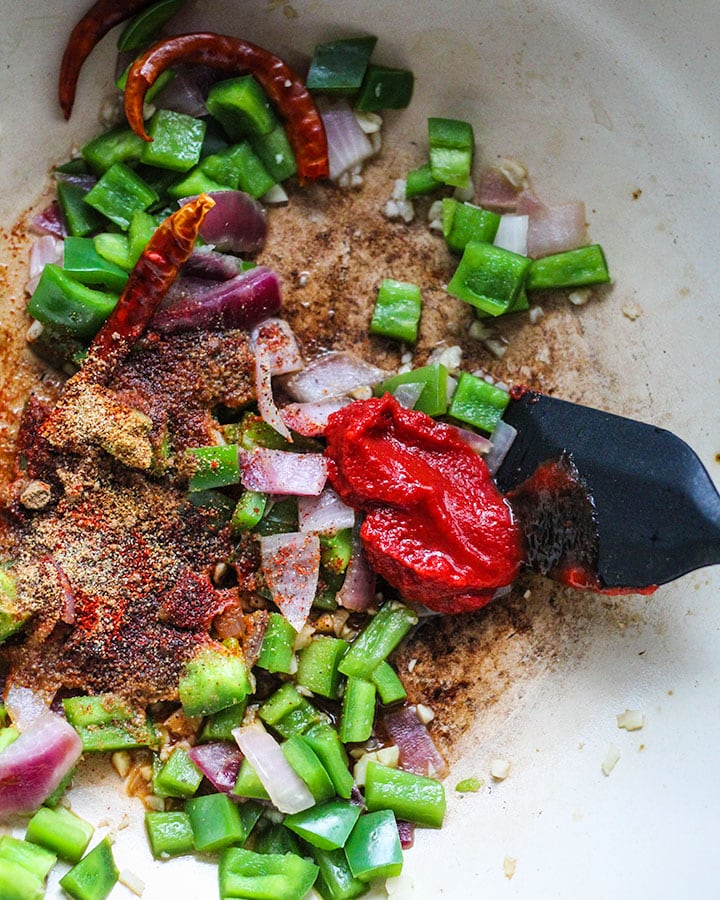 Sauteing spices with green bell pepper, onion, red chilies and tomato paste. 