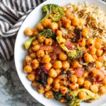 Orange chickpeas and vegetables plated with brown rice.