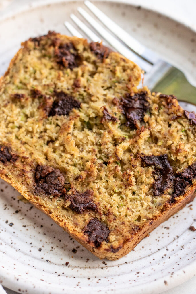 Close up of a chocolate chip zucchini bread slice with a fork tucked in the back.