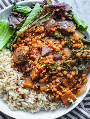 Bowl of rice topped with greens and eggplant stew.