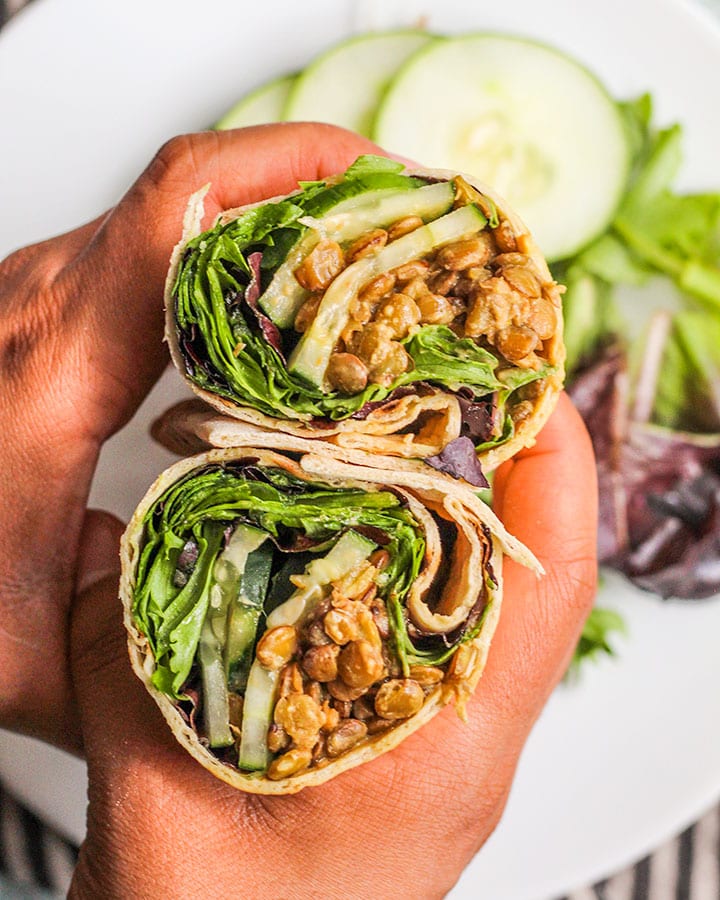 Flatlay shot of wrap cut in half with cucumber, greens and lentils.