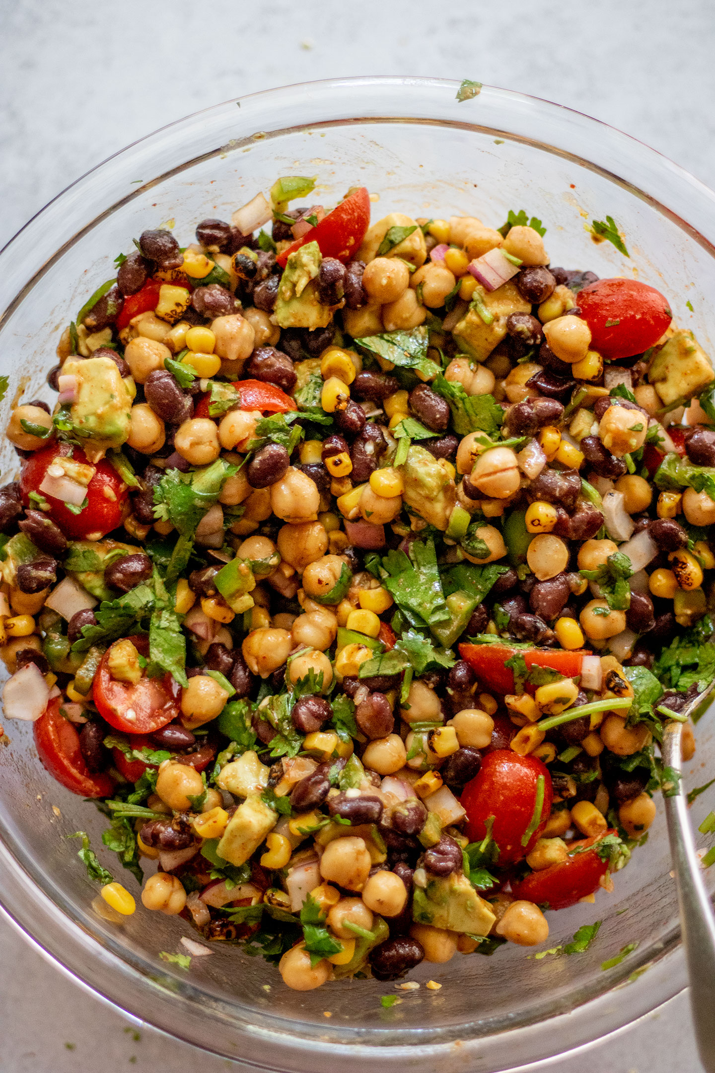 Combining the bean and corn salad with the chili lime vinaigrette in a large mixing bowl.