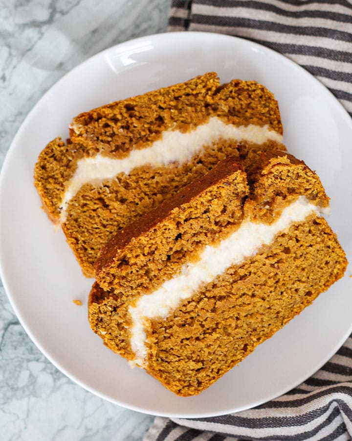 Two slices of pumpkin bread resting on a white plate and napkin.