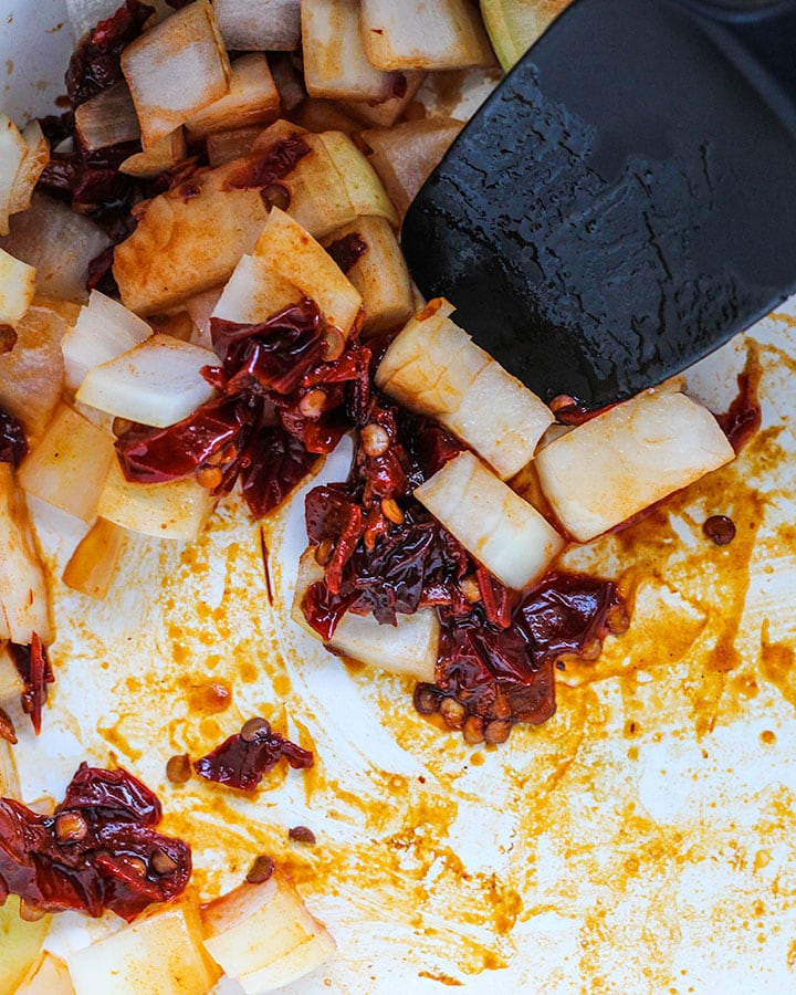 This shows diced onions and chipotle peppers being sautéed together in a large pot.