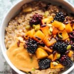 A bowl of apple oats topped with extra sauteed apples, blackberries and peanut butter.