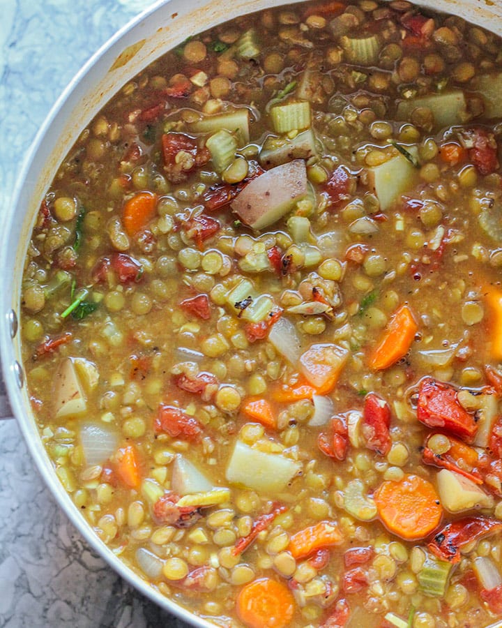 Large pot of cooked lentil soup with vegetables.