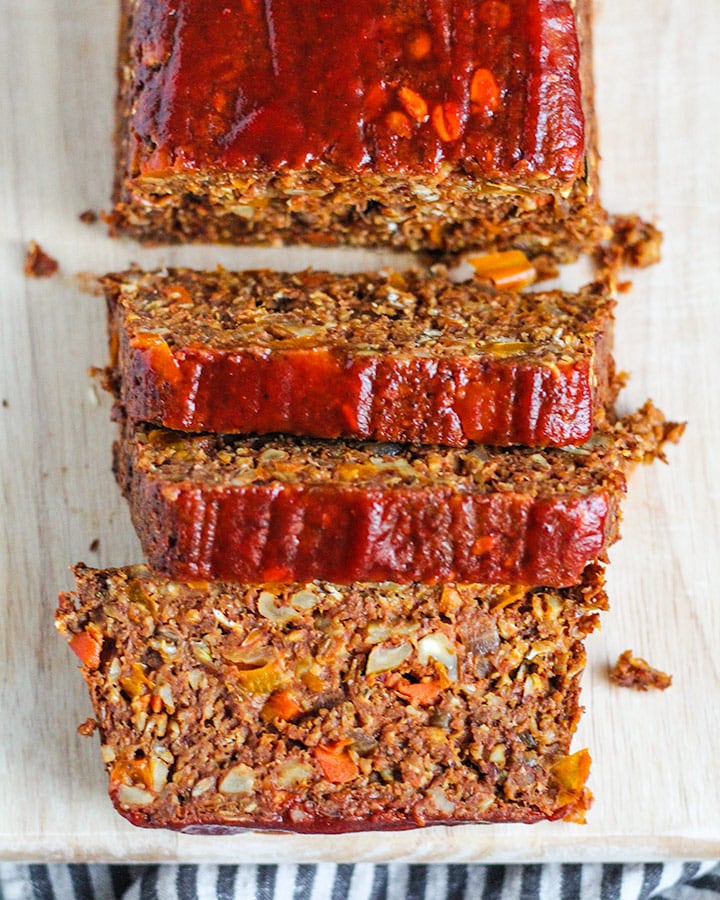 Top down shot of the lentil loaf topped with sriracha ketchup sliced for serving.