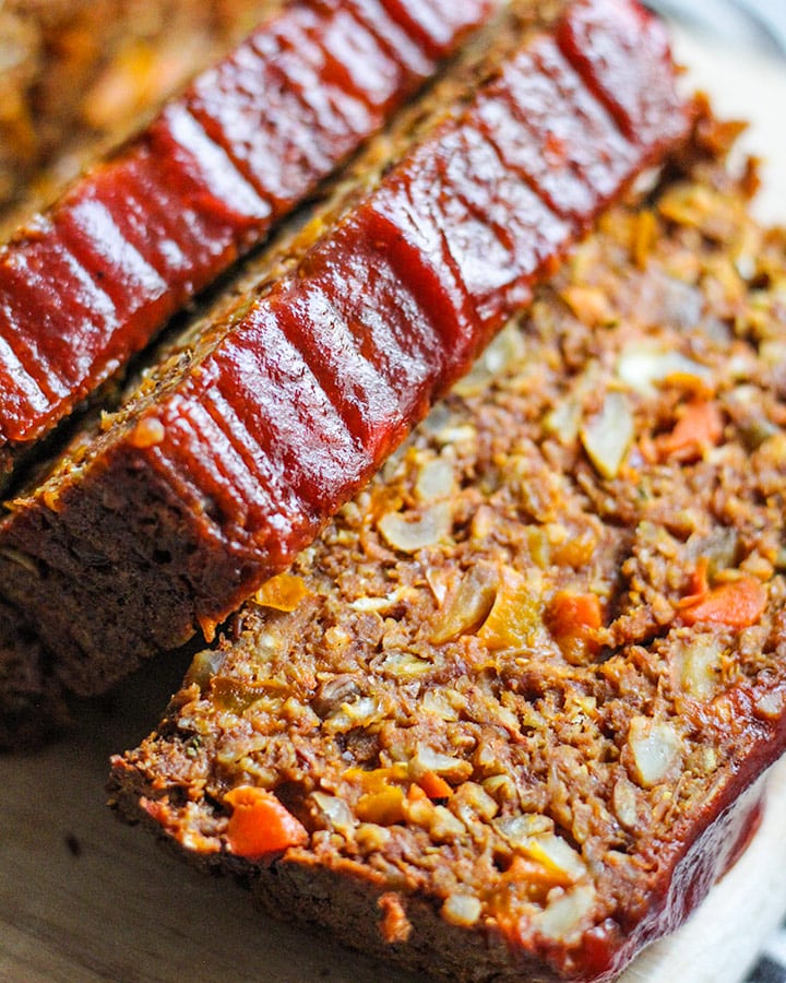Lentil loaf close up cut into slices. Each slice has a visible mix of ingredients in the middle that is firm and moist.
