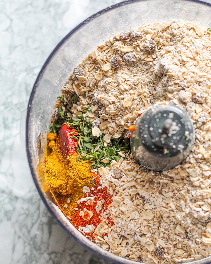 All of the lentil loaf ingredients including oats, lentils, spices, herbs, flax egg and walnuts placed in a food processor ready to process together.