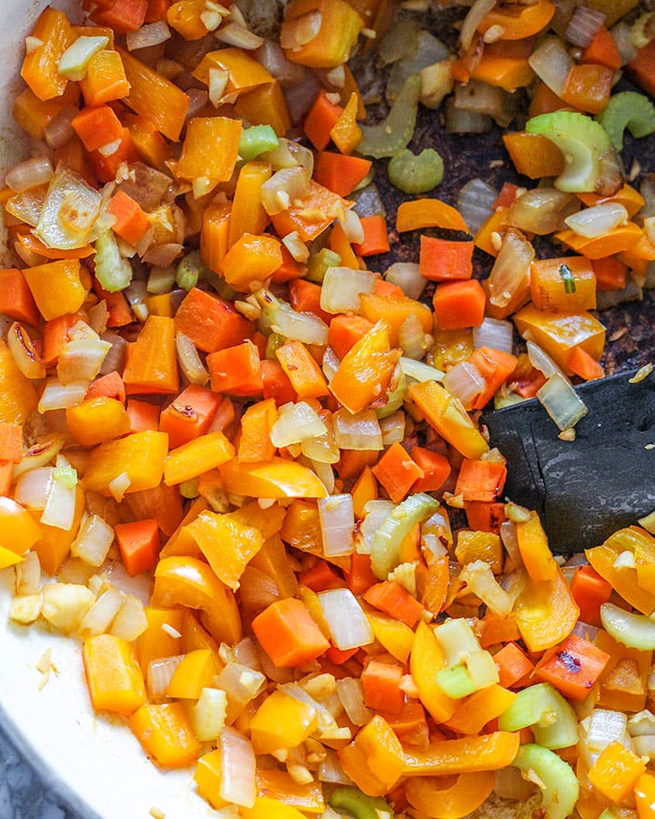 Sauteed vegetables including orange bell pepper, onion, carrots, garlic and celery all mixed together.