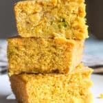 Front shot of three cornbread pieces stacked on top of each other on a plate.