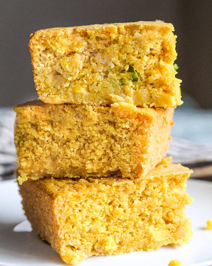 Front shot of three cornbread pieces stacked on top of each other on a plate.