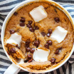 Close up of one pumpkin mug cake loaded with melted chocolate chips and marshmallows.