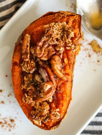 Close up of the sweet potato half with crumble, pecans, cinnamon and a drizzle of maple syrup.
