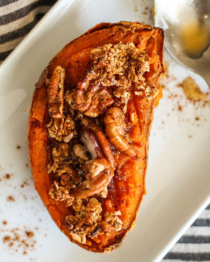 Close up of the sweet potato half with crumble, pecans, cinnamon and a drizzle of maple syrup.