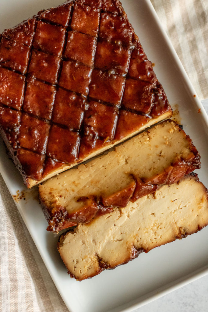 Top down view of the baked sugar glazed tofu on a white plate after being sliced.