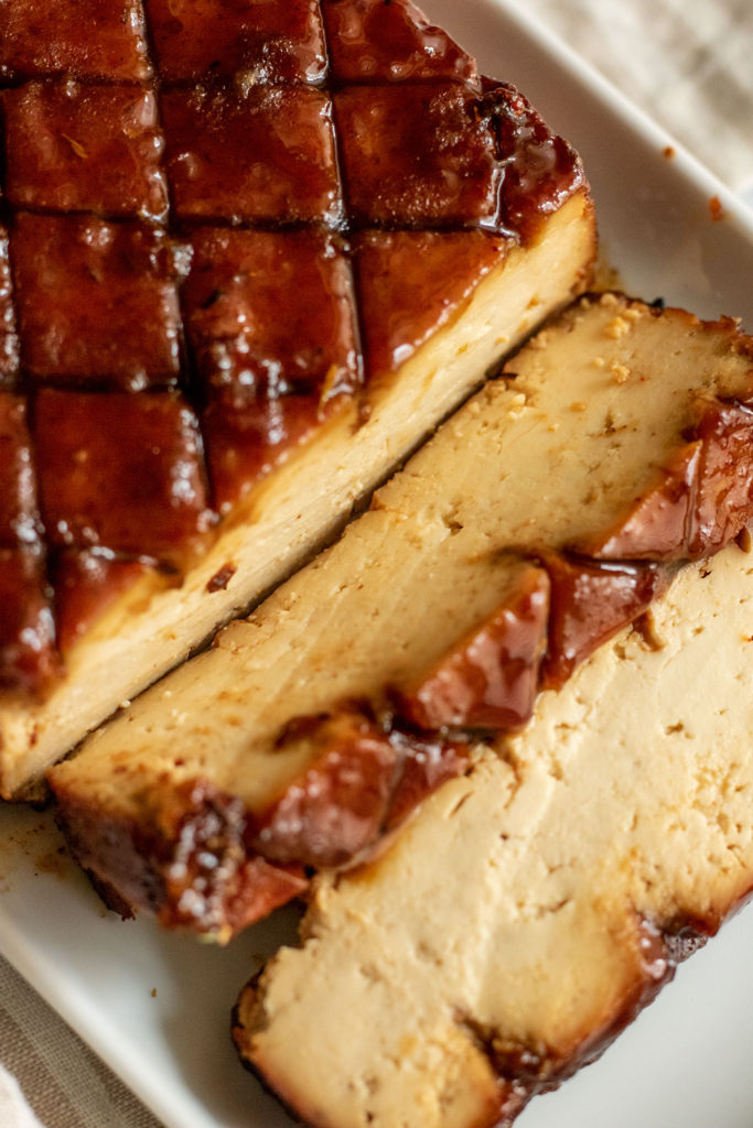 Close up view of the glazed tofu sliced on a white plate.