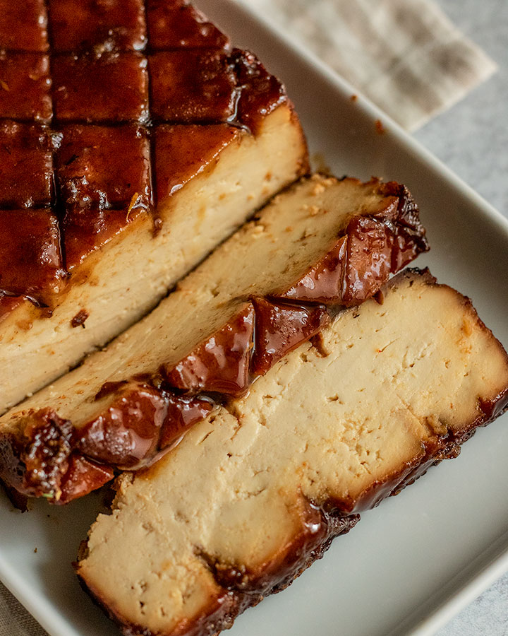 Brown sugar glazed tofu ready to serve after being sliced on a white plate.