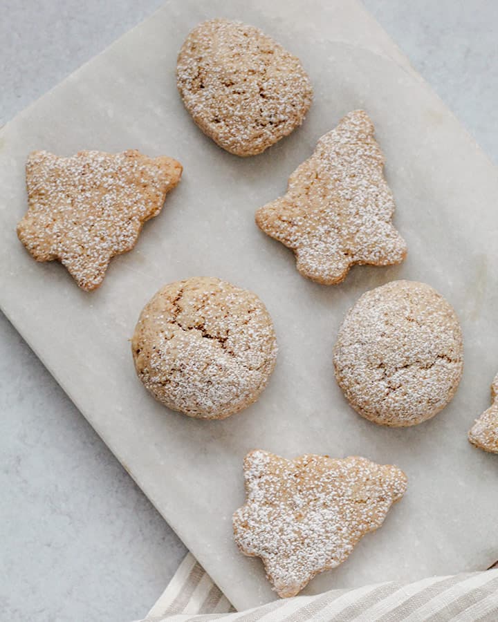 Freshly baked cut out cookies in the shape of Christmas trees, lightly dusted with powdered sugar to look like a little dusting of snow.