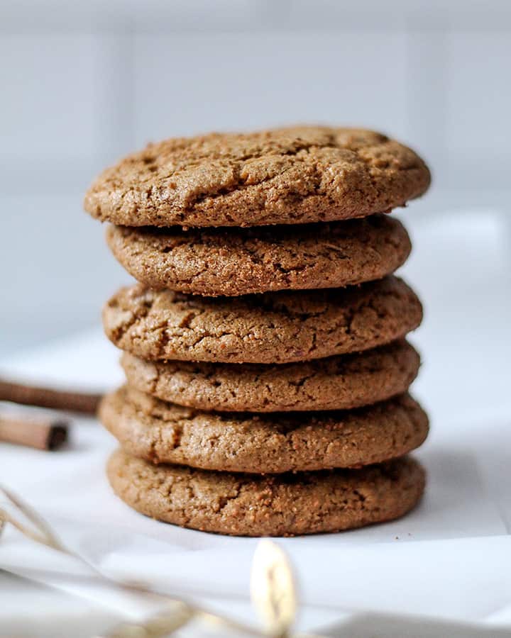 A center shot of the stack of ginger molasses cookie with cinnamon sticks in the background.