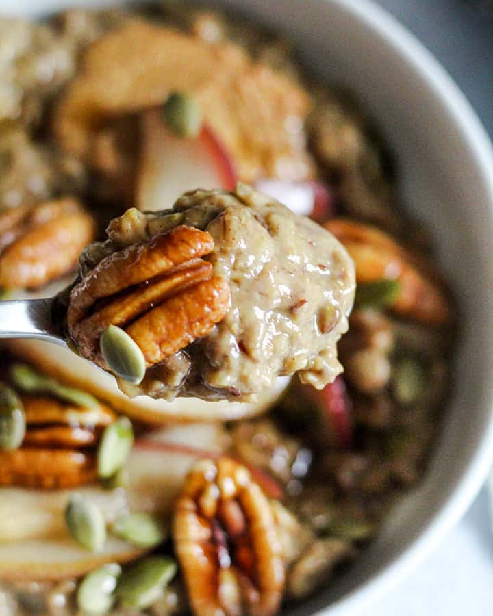 A spoonful of gingerbread oatmeal scooped along with some sautéed ginger pears and pecans.