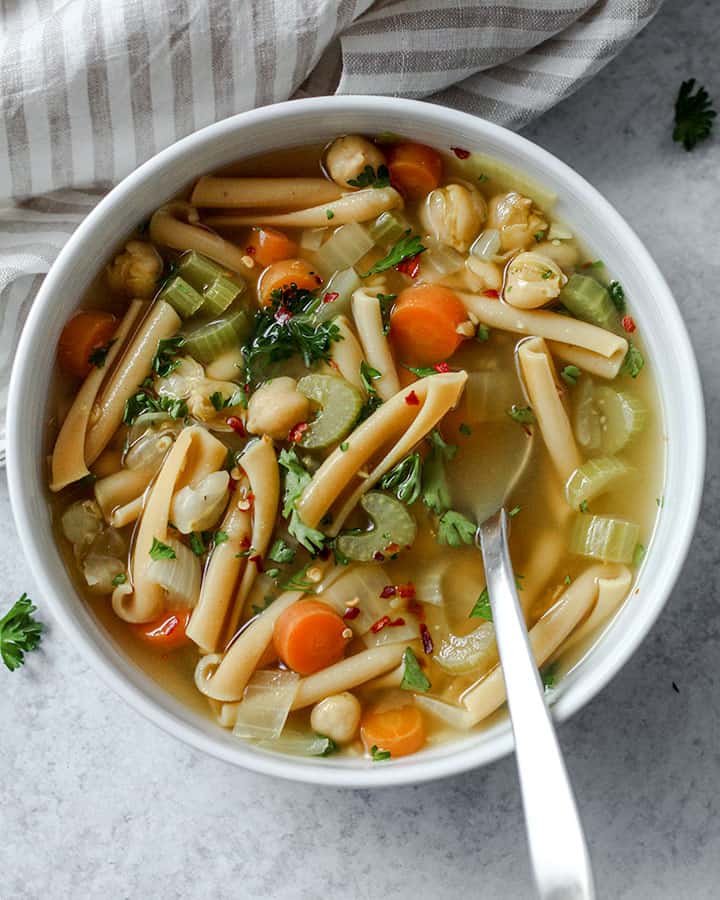 Soup in a white bowl topped with parsley with a silver spoon tucked inside ready for the first slurp.