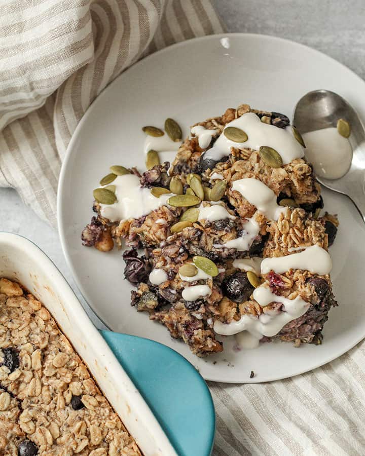 Spoonful of baked oats on a plate with pepitas and yogurt on top.