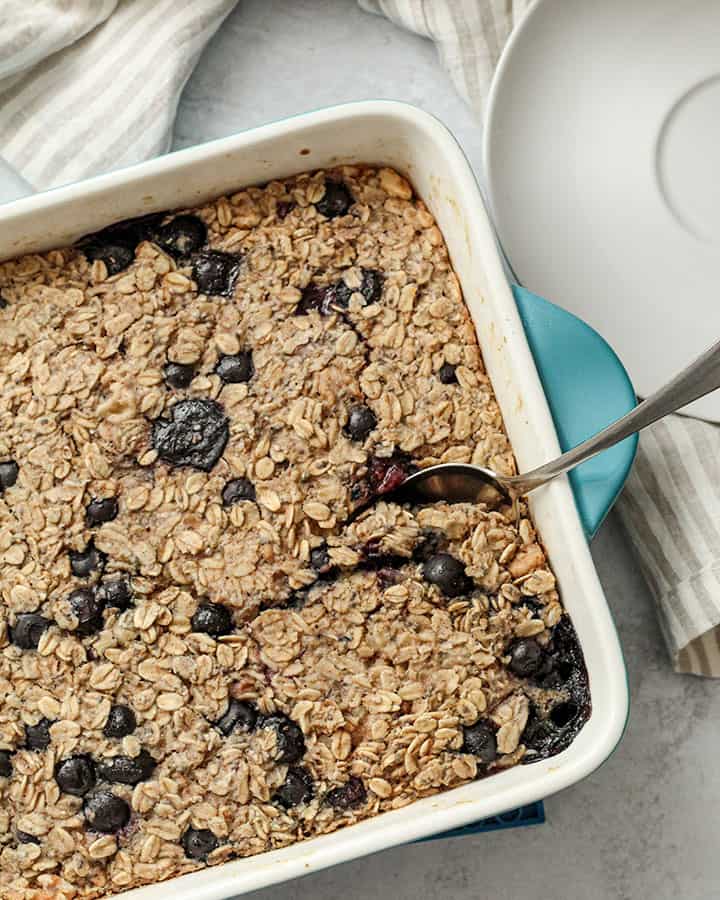 Taking a spoonful of the baked oatmeal from the baking dish with a spoon.