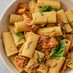 Bowl of baked hummus pasta served up with fresh basil.