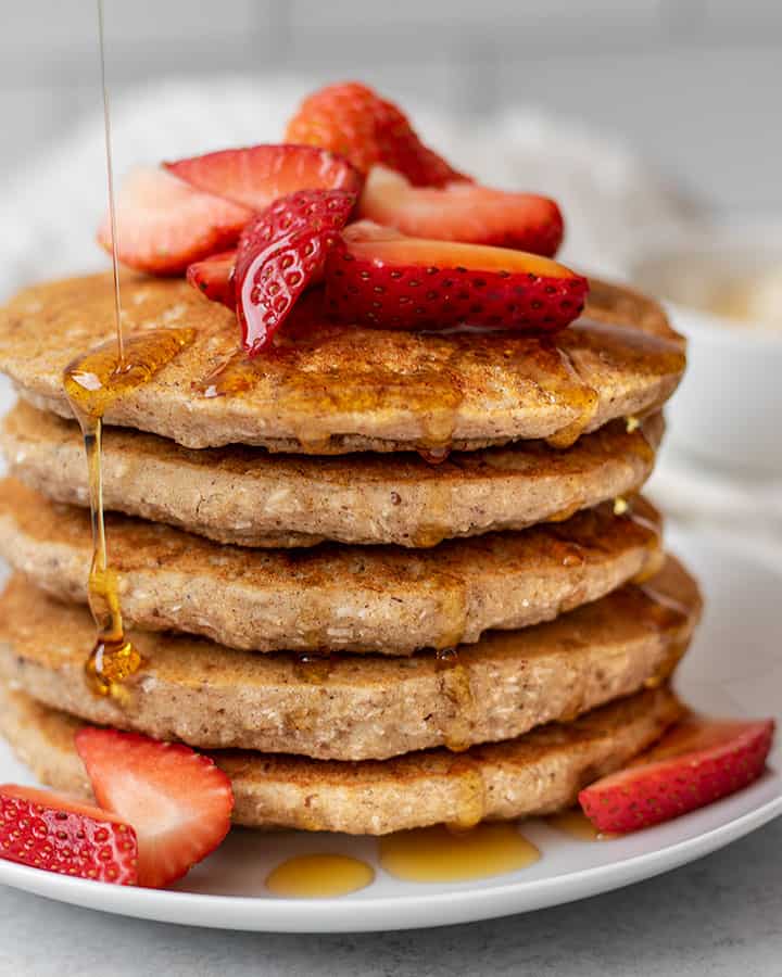 Close up view of dripping maple syrup coming from the sides of the pancakes.