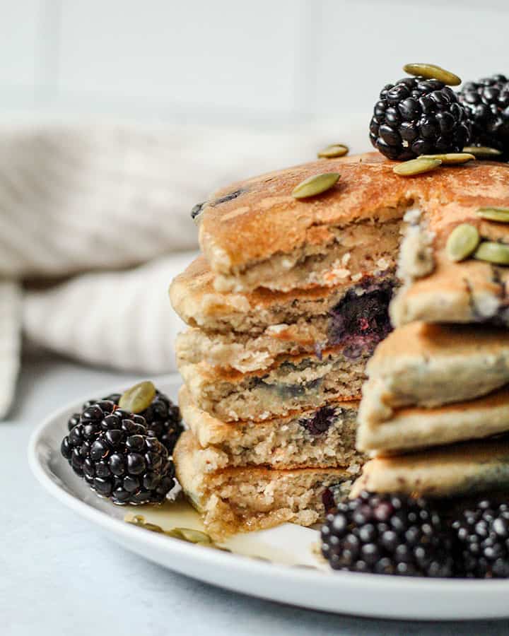 A stack of pancakes cut into with and knife showing the layers of fluffy goodness inside.