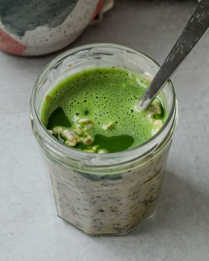 Matcha poured into the overnight oat mixture ready to mix into the oats.