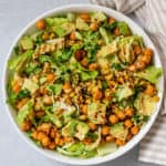 Bowl of chickpea salad topped with avocado, crispy adobo chickpeas and dressing.
