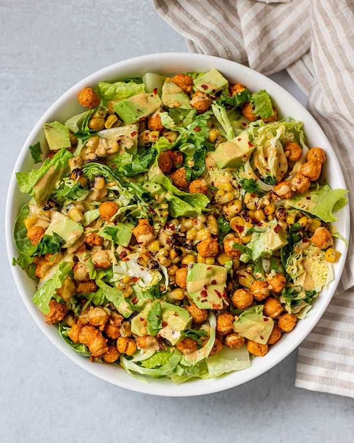 Bowl of chickpea salad topped with avocado, crispy adobo chickpeas and dressing.