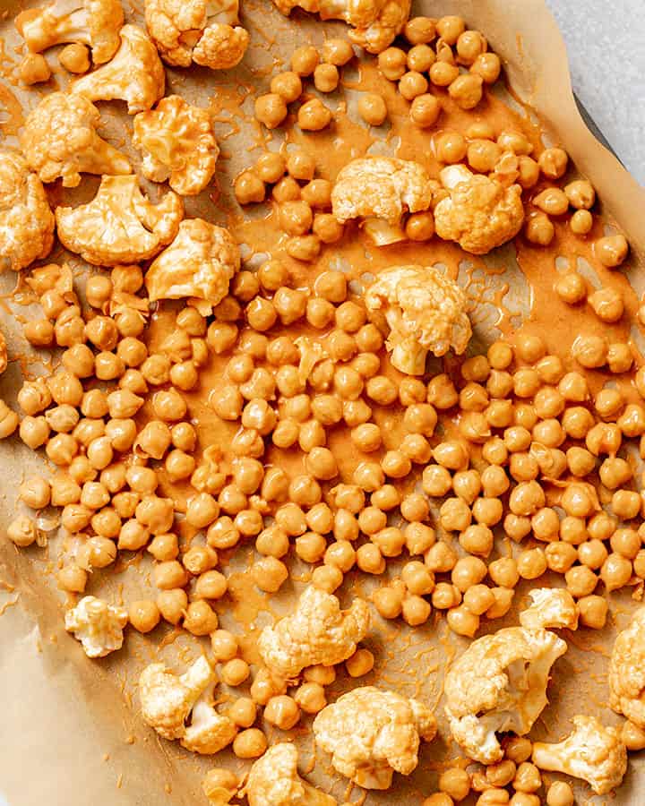 Coating chickpeas in the buffalo sauce and spreading out on a baking pan.